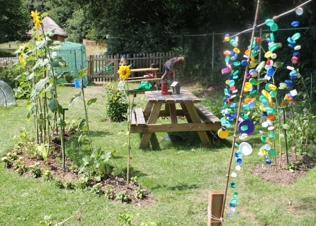 Midfield Primary School garden's picnic table surrounded by sunflowers and brightly coloured suncatchers