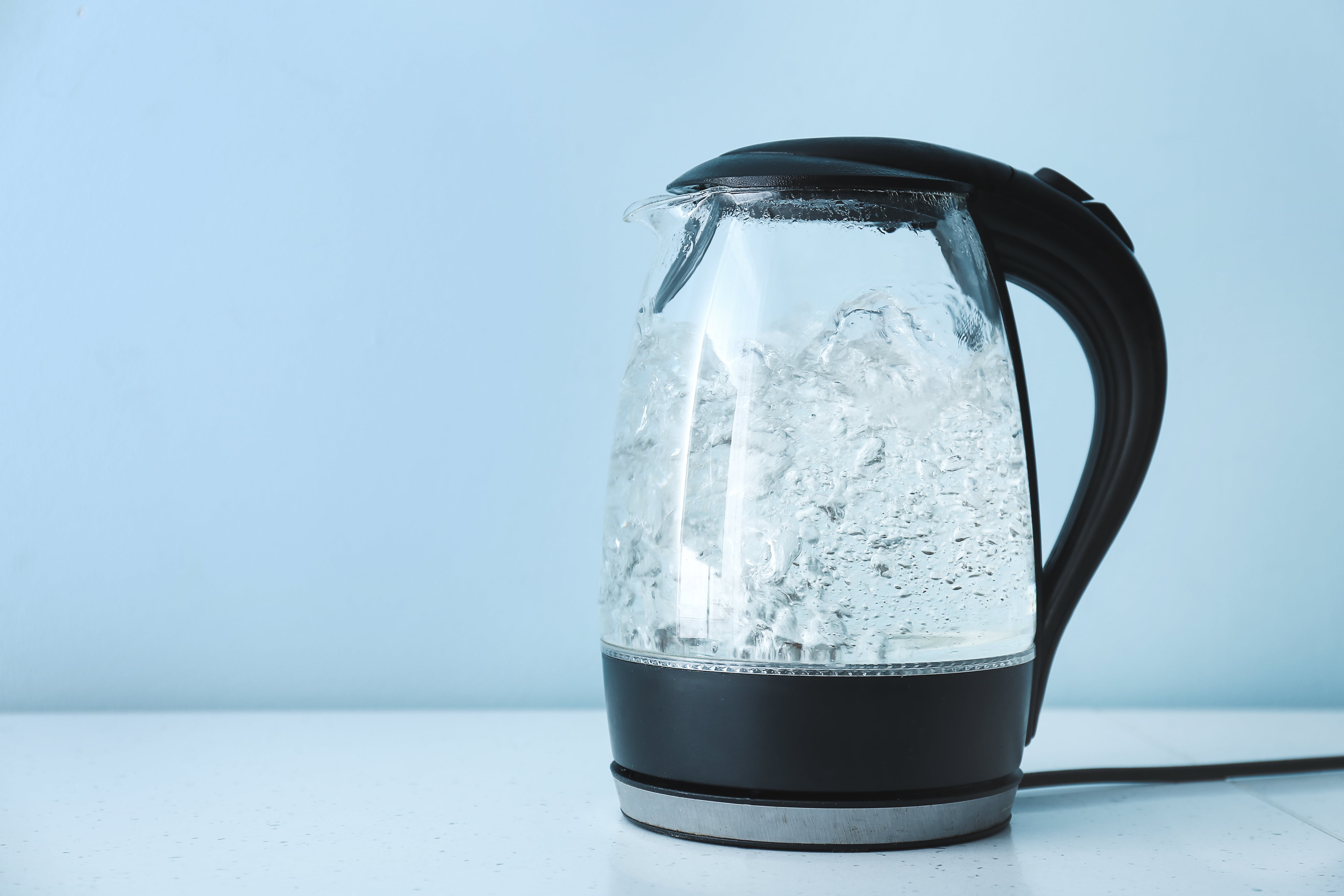 Transparent electric kettle with boiling water on table