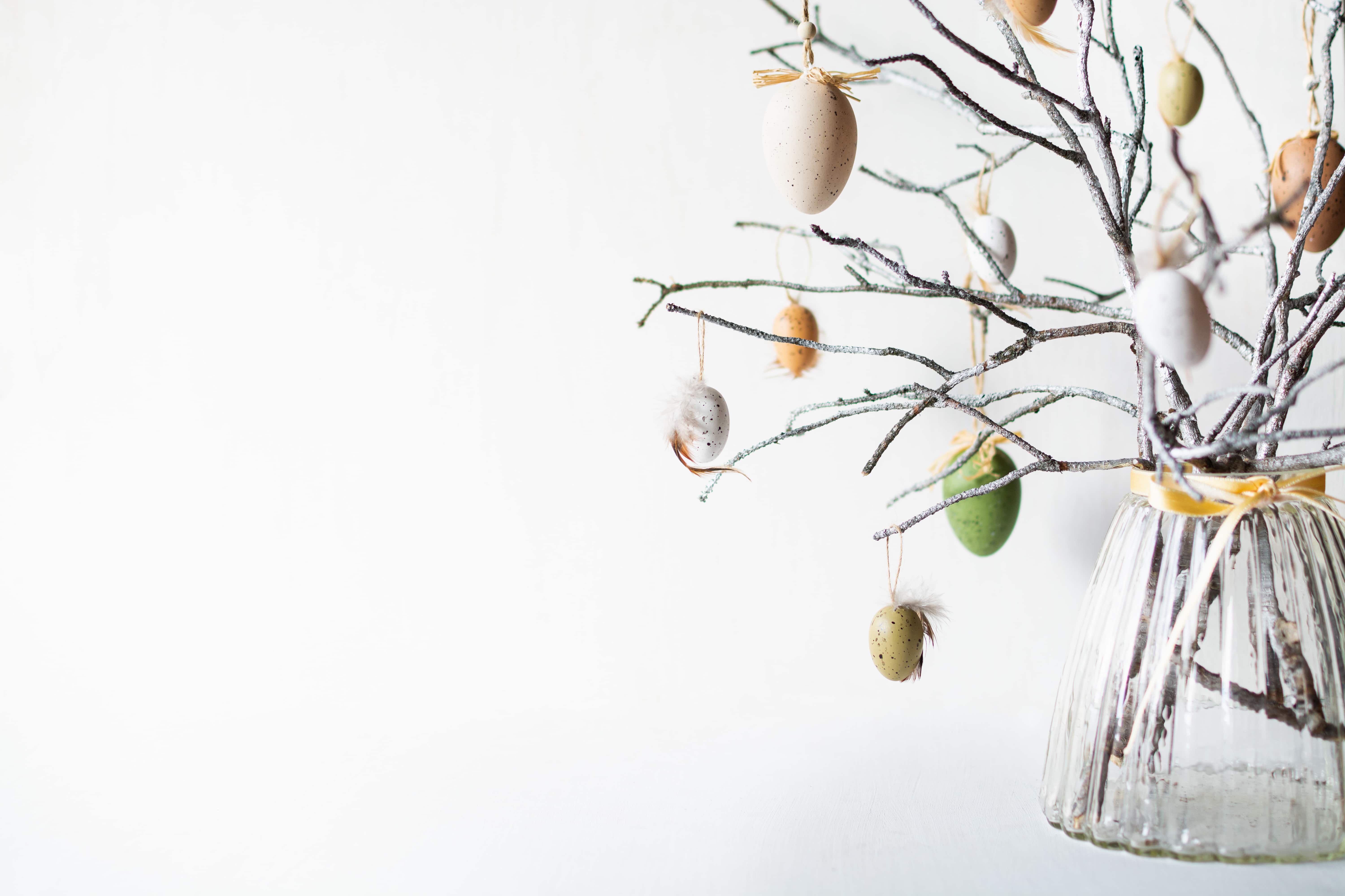 Still life with tree branches decorated with Easter eggs and feathers in a glass vase