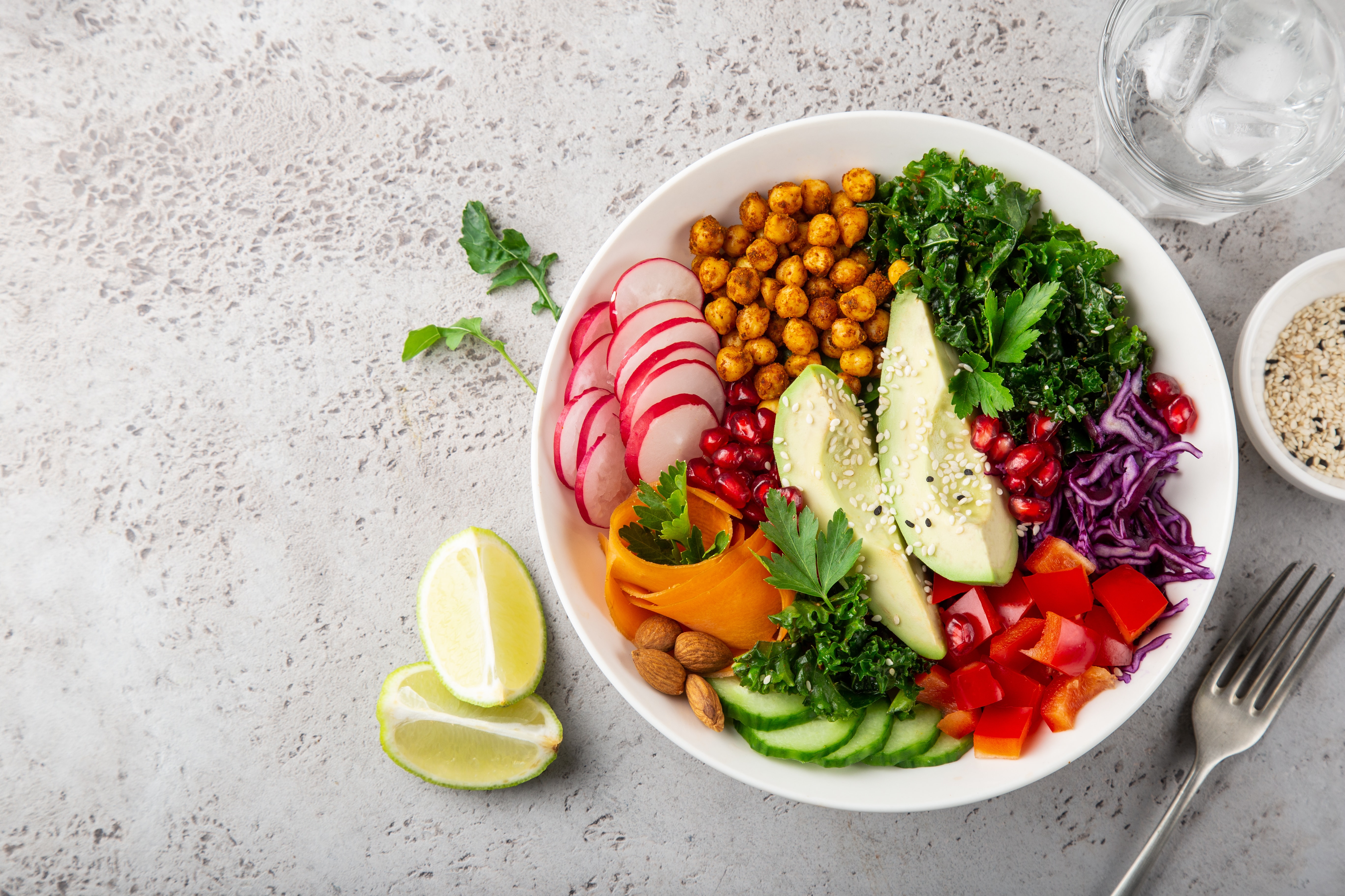 lunch bowl salad with avocado, roasted chickpeas, kale, cucumber, carrot, red cabbage, bell pepper and redish, healthy vegan food, top view, copy space