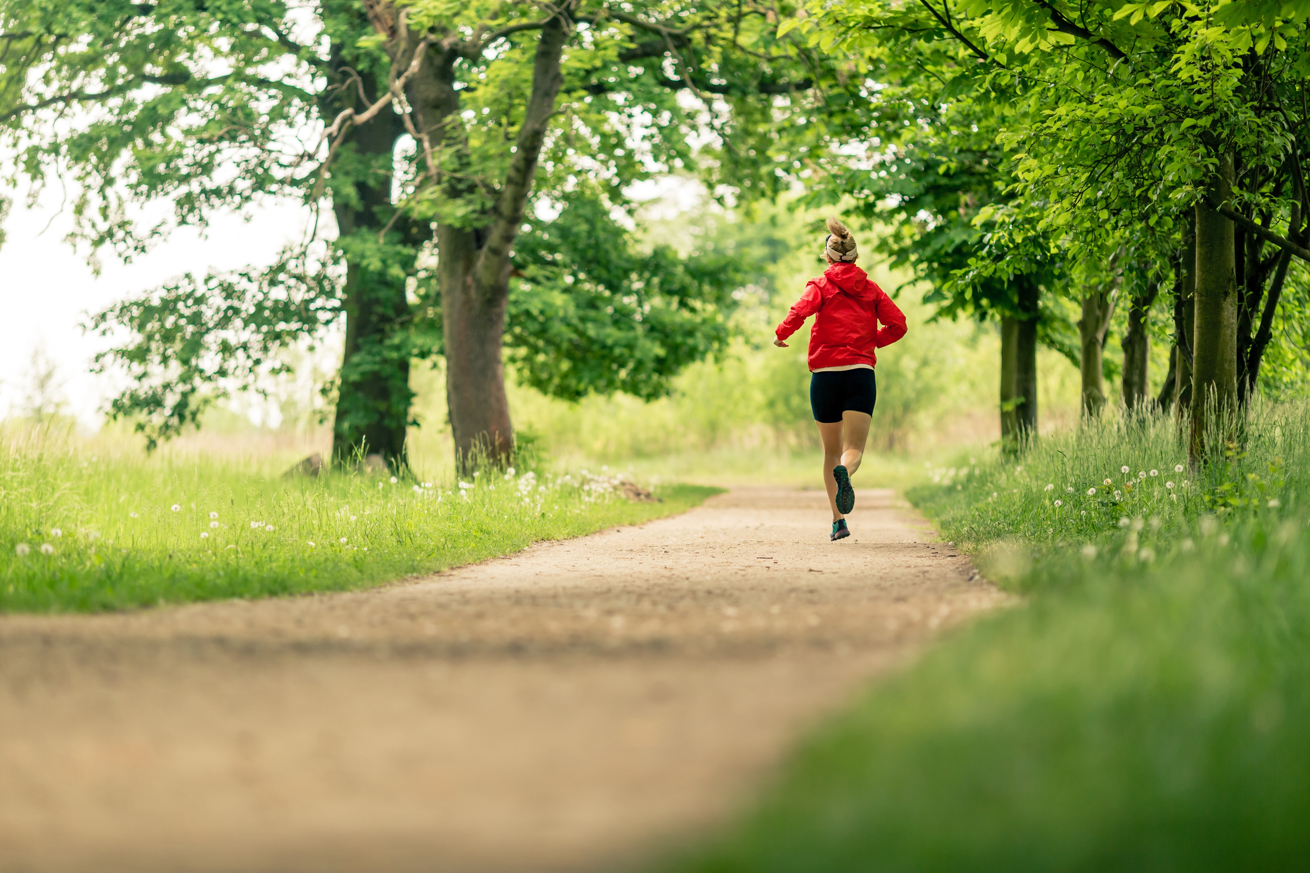 Running woman, enjoying summer day in park. Endurance training, jogging or power walking female athlete, physical activity concept outdoors.