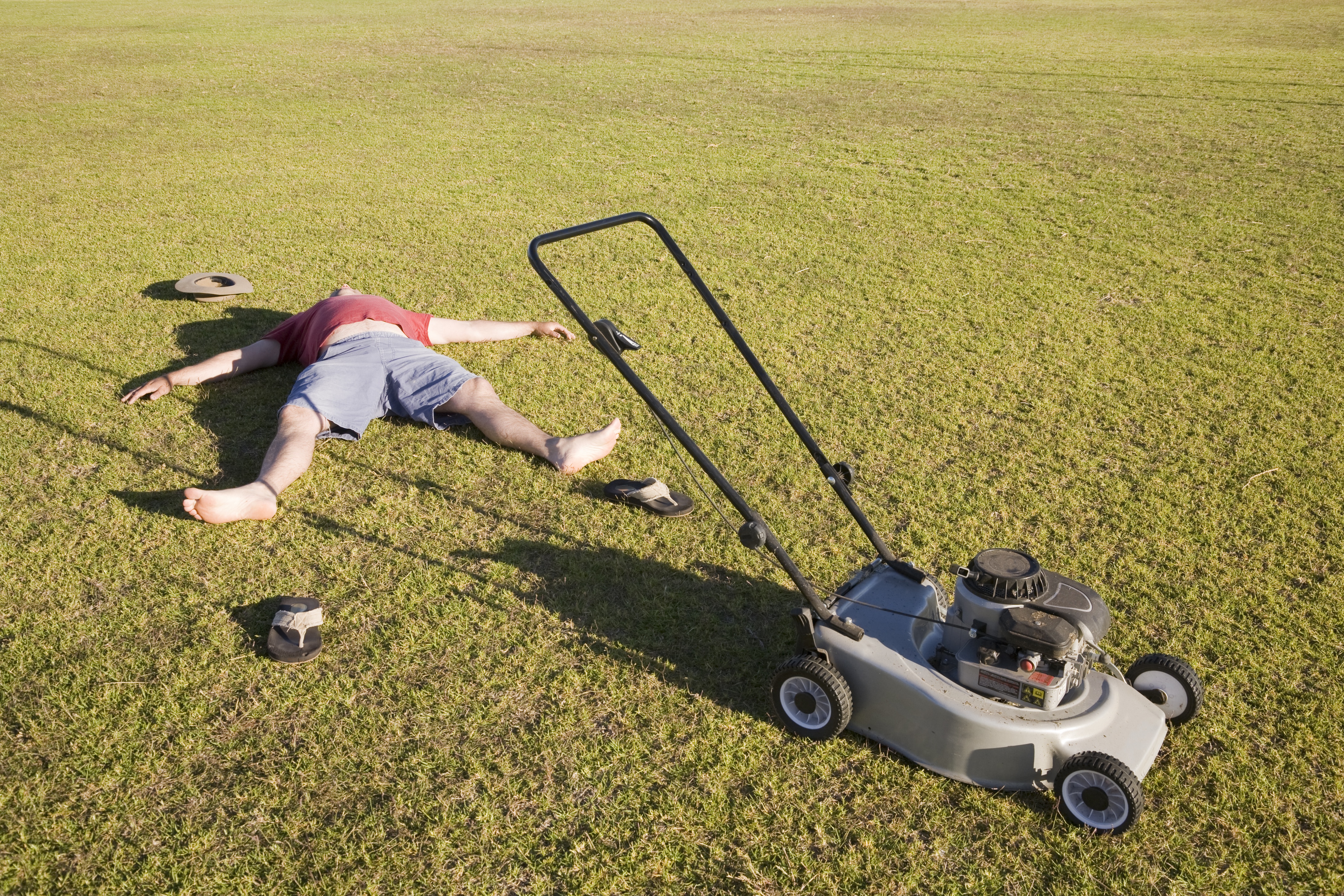 An exhausted man lying on the ground collapsed after mowing a huge lawn.