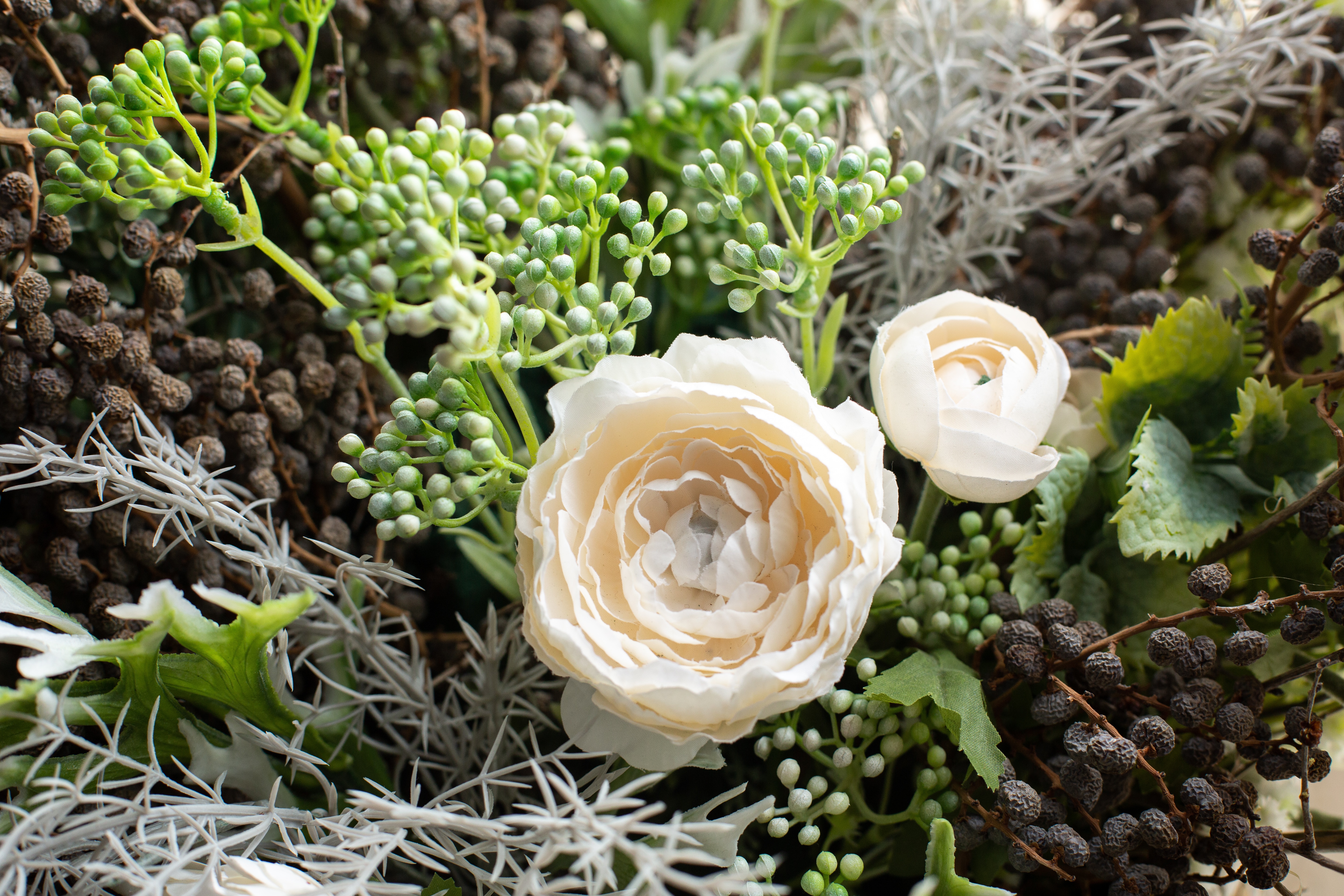 Arrangement of white flowers and dried flowers in a wicker basket side view