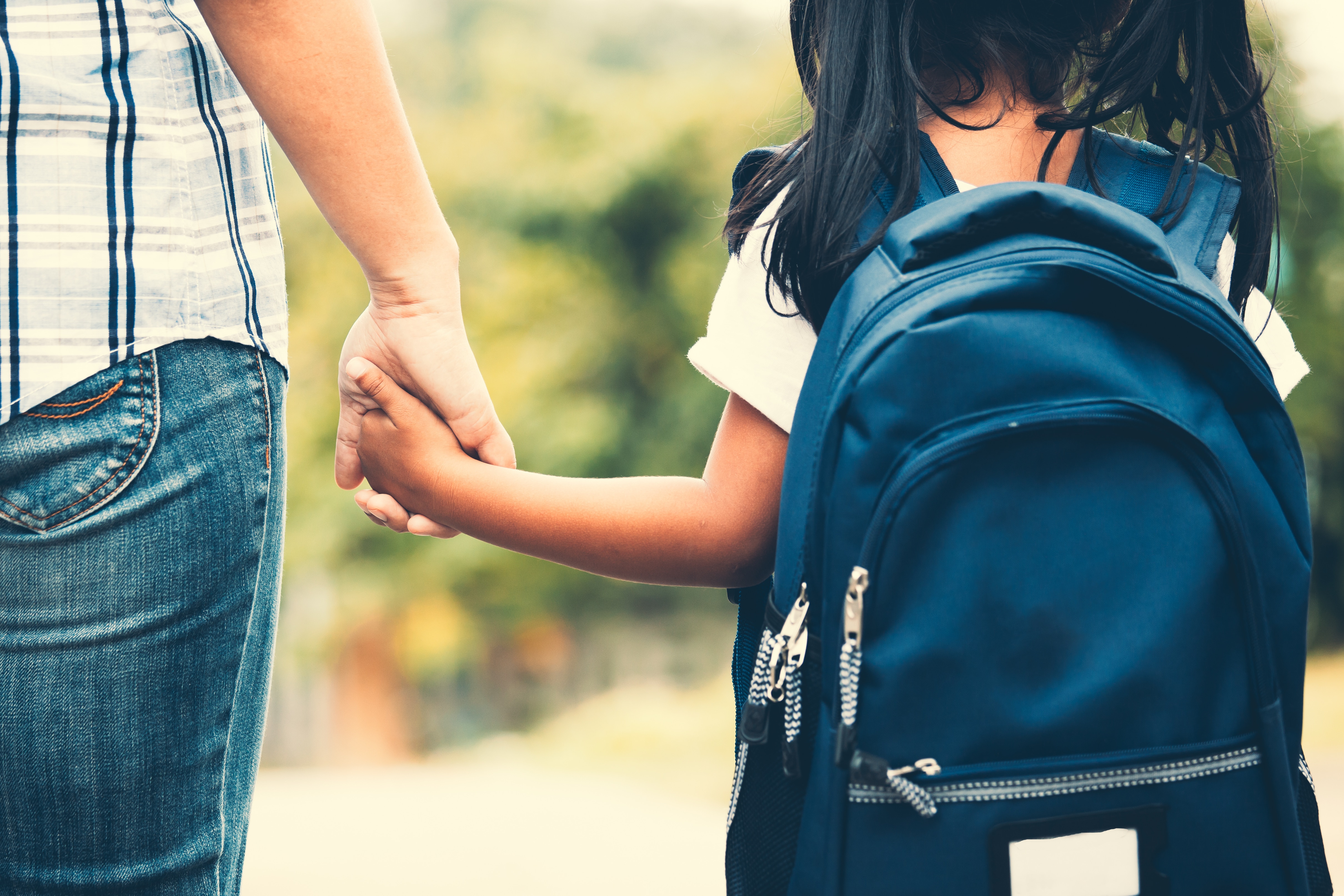 Back to school. Cute asian pupil girl with backpack holding her mother hand and going to school in vintage color tone